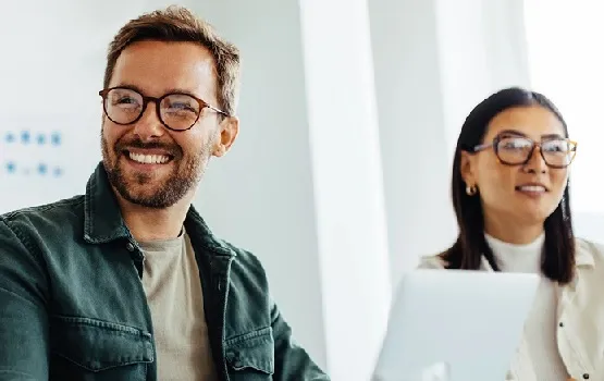 Two people working on laptops together in a modern workspace, representing access to up‑to‑date career insights and advice.