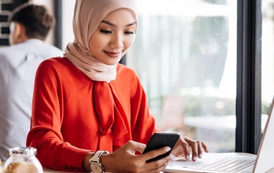 Person using a smartphone at a desk, representing managing job applications and career tasks on the go.