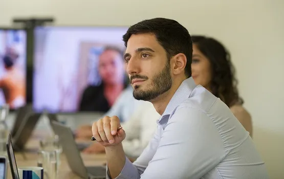 Professional working at a desk with a colleague in the background, representing Hays Total Workforce Solutions for integrated hiring and streamlined workforce management.