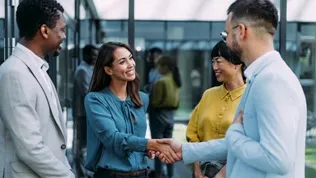 Several professionals in conversation in a modern office environment, representing collaboration within an international business setting.